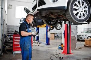 tema de reparación y mantenimiento de automóviles. mecánico en uniforme que trabaja en el servicio de automóviles. foto