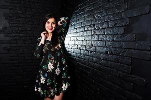 retrato de una joven fabulosa vestida de flores en el oscuro estudio. foto