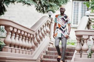 Handsome afro american man wearing traditional clothes, cap and eyeglasses in modern city. photo