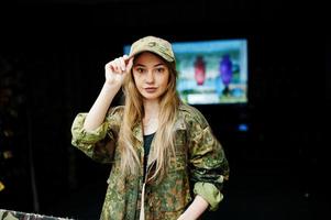 niña militar en uniforme de camuflaje contra el fondo del ejército en el campo de tiro. foto