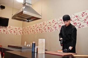 Professional chef wear in black making sushi and rolls in a restaurant kitchen of japanese traditional food. photo