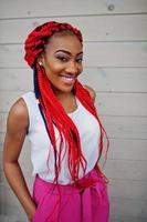 Fashionable african american girl at pink pants and red dreads posed outdoor. photo