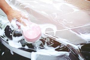 people man holding hand pink sponge for washing car. Concept car wash clean. photo