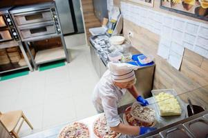 Female chef preparing pizza in restaurant kitchen. photo