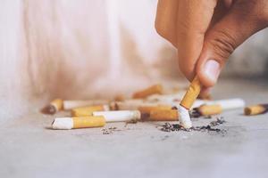 Hand putting out a cigarette,cigarette butt on Concrete floor, bare cement. photo