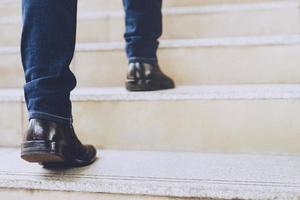 Close up legs shoes of young business man One person walking stepping going up the stairs in modern city, go up, success, grow up. with filter Tones retro vintage warm effect. stairway photo