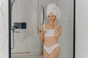 Young lady enjoying morning anti age anti wrinkle routine in bathroom photo