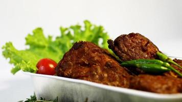 champiñones de soja fritos, tomates pequeños, chiles y ensalada en un recipiente de aluminio. típica comida callejera indonesia de fondo blanco foto