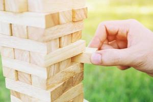 people hand playing take one brown wood block stack game on building tower. concept planning risk and strategy in and engineer construction. photo