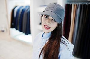 hermosa chica morena en la boutique de la tienda de ropa en ropa casual y gorra. foto