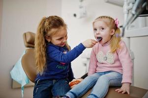 Two cutie little baby girls at dentist chair. Children dental. photo