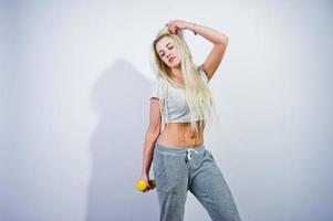 Blonde sporty girl with yellow dumbbell posed at studio against white background. photo