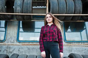 Young hipster girl in checkered shirt at tire fitting zone. photo