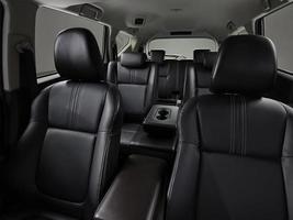 The black seats in modern cars parked outdoors in the garden show both the front and rear seats. photo