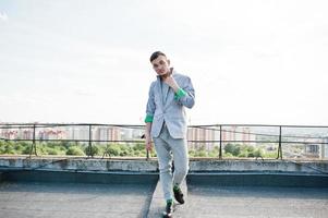 Dreamer stylish macho man in gray suit and glasses posed on the roof. photo