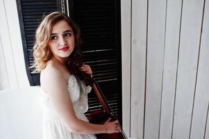 Pretty young gilrl musician in white dress with double bass. photo