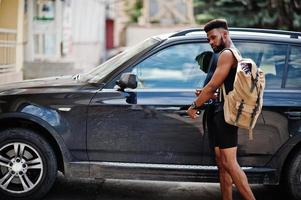 African american male athlete sport man with backpack against his black suv car before training. photo