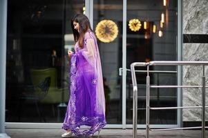 niña hindú india en el sari violeta tradicional posó en la calle. foto
