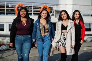 Group of four happy and pretty latino girls from Ecuador posed against boat. photo