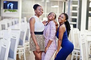 Three african woman in dress posing at restaurant. photo