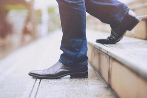 primer plano de las piernas del hombre de negocios bajando las escaleras. la gente del trabajo camina hacia abajo y se desespera. y concepto de desempleo. foto