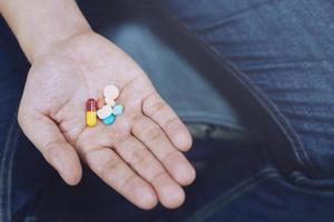 close up hand man taking multiple colors pills in hand. Stop drug use Taking Medication health care medical concept photo