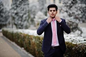 elegante modelo de hombre macho indio con traje y corbata rosa posado en el día de invierno. foto