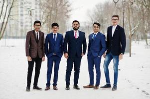 grupo de cinco empresarios indios en trajes posados al aire libre en un día de invierno en europa. foto