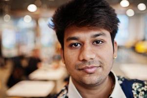 Close up portrait of young male indian freelancer in fast food cafe, handsome head of asian man wear in shirt at comfortable coffee shop. photo