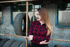 Young hipster girl in checkered shirt at tire fitting zone. photo