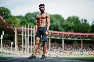 African american male athlete sexy sport bare torso man with running sports arm case for mobile phone, posed at stadium. photo