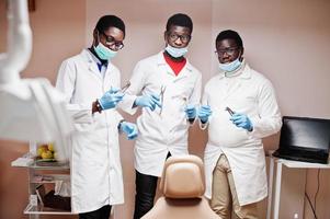 Three african american male doctors colleagues with tools at hands in clinic. photo
