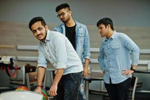 tres amigos asiáticos en traje de jeans jugando bolos en el club. foto