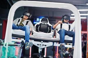 Two young indian people having fun with a new technology of a vr headset at virtual reality simulator. photo