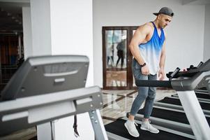 Fit and muscular arabian man running on treadmill in gym. photo