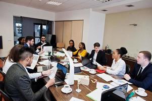 jóvenes creativos multirraciales en la oficina moderna. grupo de jóvenes empresarios están trabajando juntos con laptop, tablet. exitoso equipo de freelancers en coworking. foto