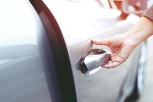 Close up image of a businessman hand on handle opening a car door. Pull the door to you. photo