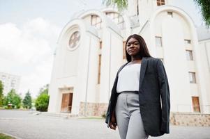 mujer afroamericana al aire libre contra la iglesia y reza a Dios. concepto de fe, espiritualidad y religión. foto