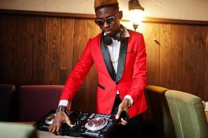 moda hombre afroamericano modelo dj en traje rojo con controlador de dj. foto