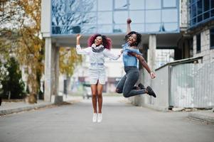 Two attractive african american womans jumping against modern multistory building. photo