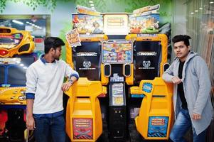 Two asian guys compete on speed rider arcade game racing simulator machine. photo