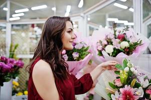 Brunette girl in red buy flowers at flower store. photo