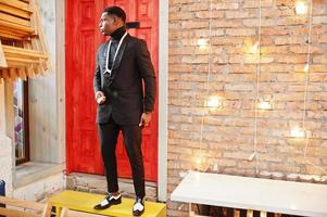 Strong powerful african american man in black suit and turtleneck, afro beads necklace and elephant tusk. photo