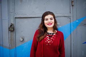 Brunette plus size model at red against colored wall. photo