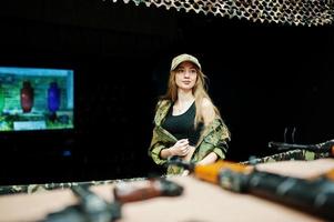 niña militar en uniforme de camuflaje contra el fondo del ejército en el campo de tiro. foto