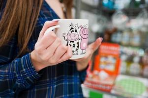 mujer de compras mirando los estantes del supermercado. retrato de una niña en una tienda de mercado sosteniendo una taza. foto