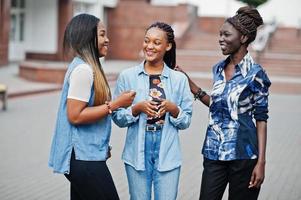 Group of young black female friends hanging out in the city. Multiracial african women walking by the street and discuss. photo