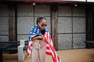 Stylish african american woman in sunglasses posed outdoor with usa flag. photo