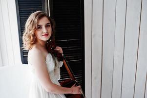 Pretty young gilrl musician in white dress with double bass. photo