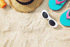 Some Beach accessories. hat ,Sandals slippers,sunglasses,sunblock lotion on the sandy shore on the summer sands of the sea. with copy space on the below side. Concept of travel summer vacations sea. photo